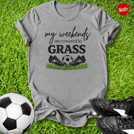 Gray t-shirt with 'my weekends are covered in grass' text and soccer ball graphic on grass with soccer shoes and ball.