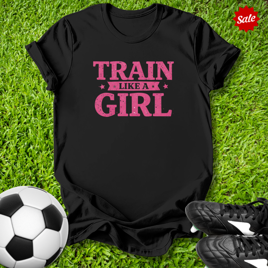 Black t-shirt with 'Train Like a Girl' text on grass with soccer ball and shoes