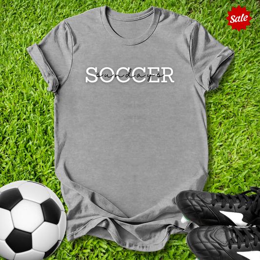Gray t-shirt with 'Soccer Saturdays' text on grass with soccer ball and shoes