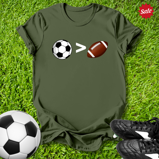 Green t-shirt with sports-themed graphic on grass with soccer ball, football, and shoes.