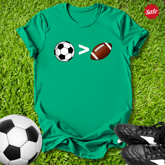 Green t-shirt with sports-themed design on grass, surrounded by soccer ball and football