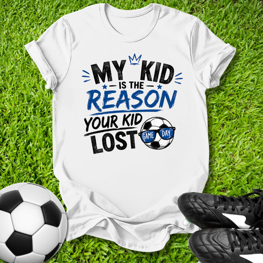 White t-shirt with humorous My Kid is the Reason Your Kid Lost text soccer-themed text on grass with soccer ball and shoes.