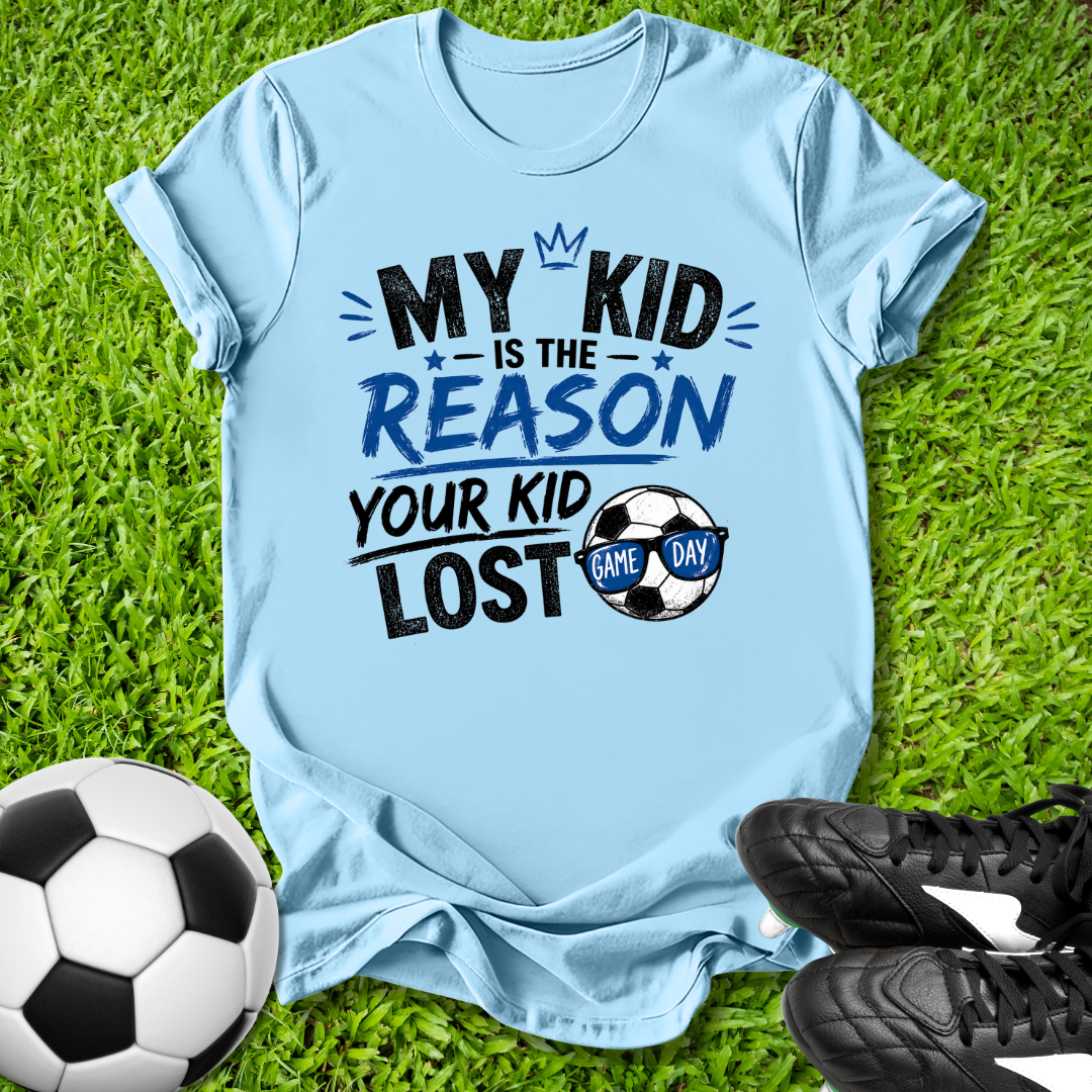 Blue t-shirt with humorous My Kid is the Reason Your Kid Lost text soccer-themed text on grass with soccer ball and shoes.