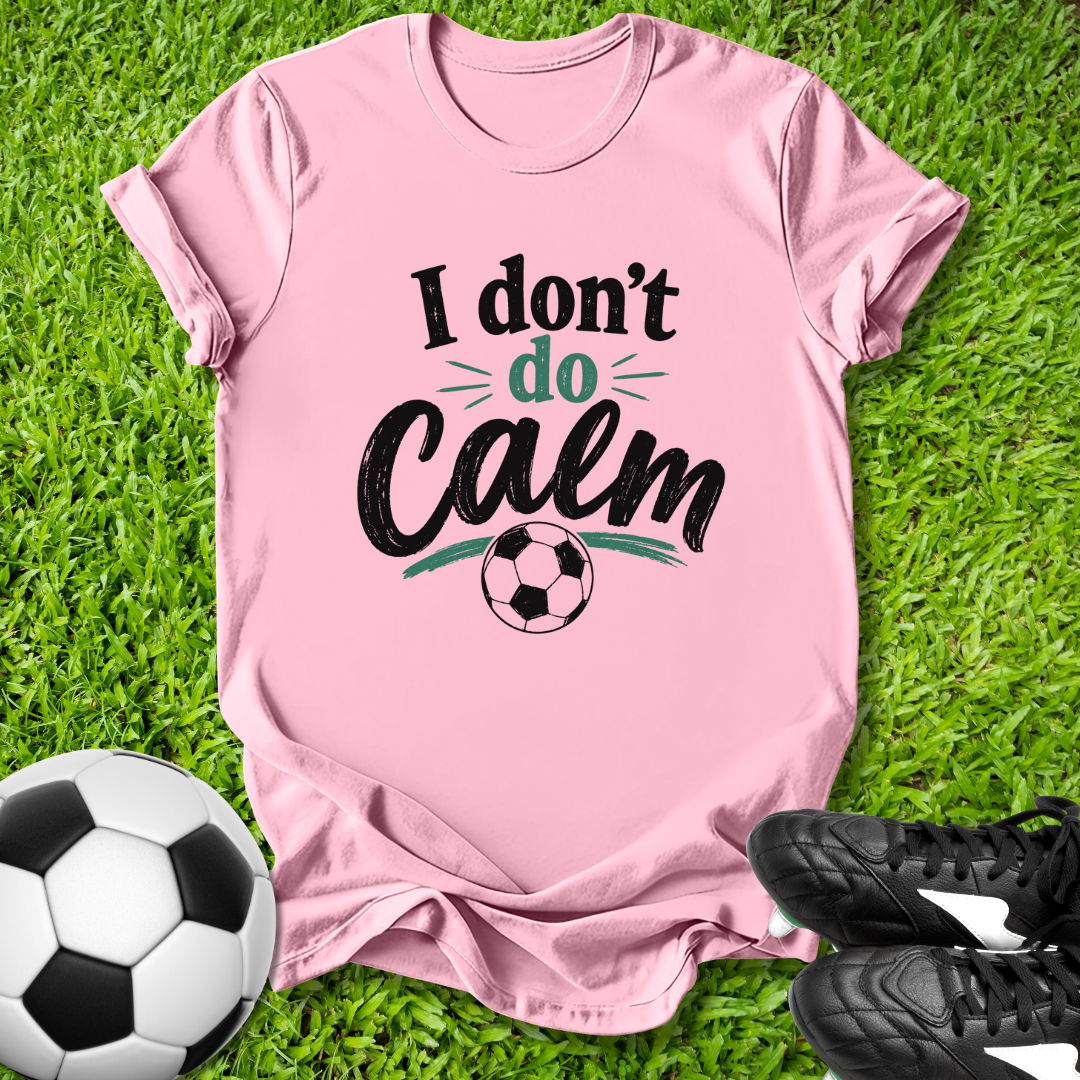 Pink t-shirt with 'I don't do calm' text on grass with soccer ball and shoes
