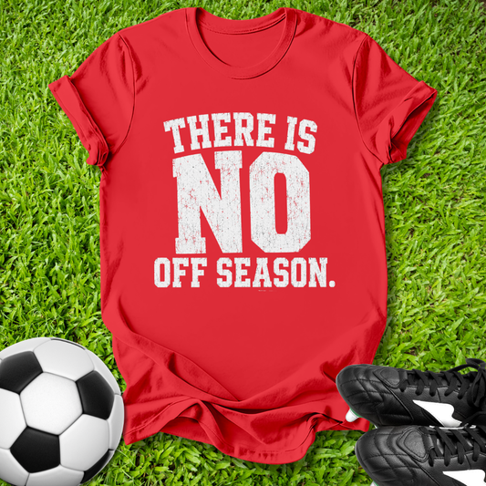 Red t-shirt with 'There is no off season' text on grass with soccer ball and shoes.