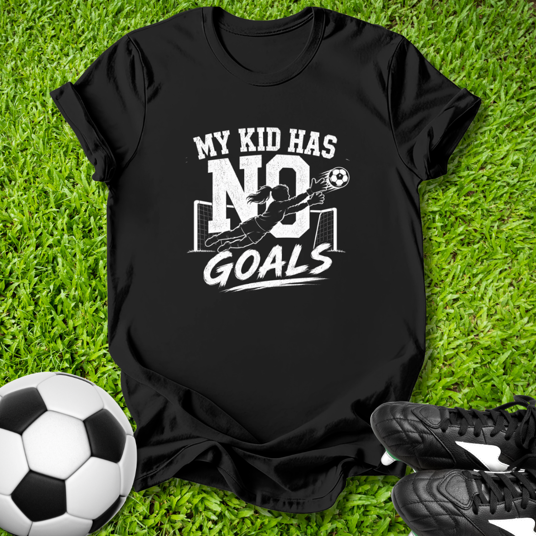 Black t-shirt with 'My kid has no goals' print on grass with soccer ball and shoes.