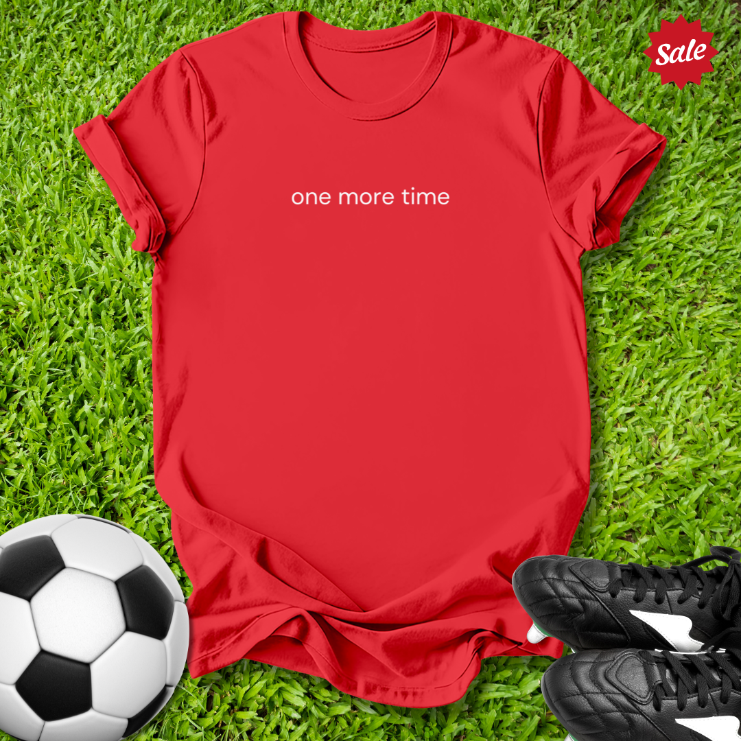 Red t-shirt with 'one more time' text on grass with soccer ball and shoes