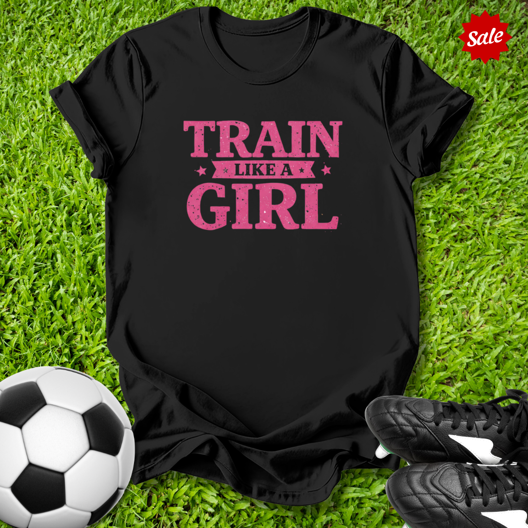 Black t-shirt with 'Train Like a Girl' text on grass with soccer ball and shoes
