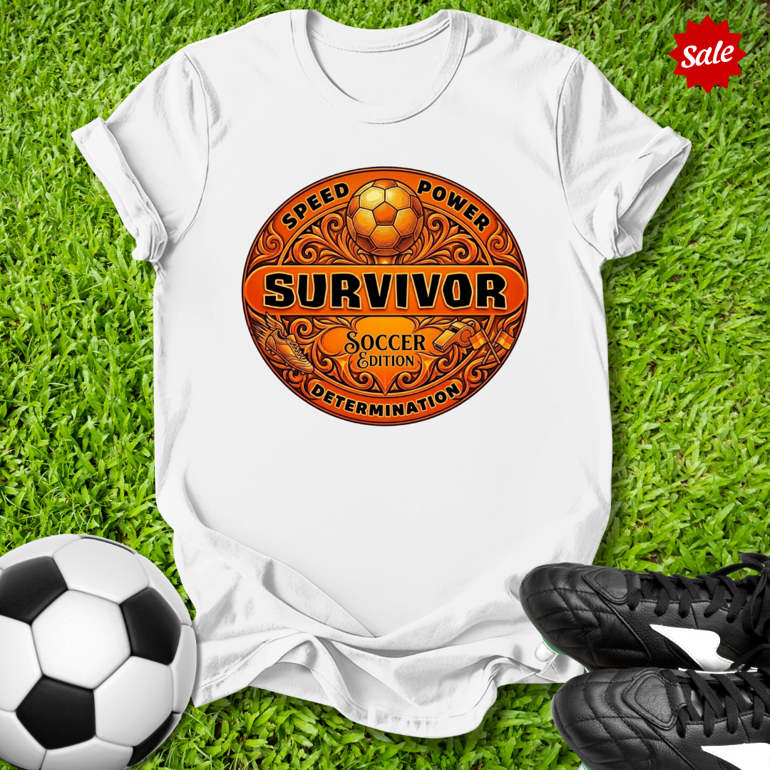 White t-shirt with a Survivor soccer-themed design on grass with a soccer ball and shoes.