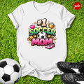 White t-shirt with '#1 Soccer Mom' design on grass with soccer ball and shoes