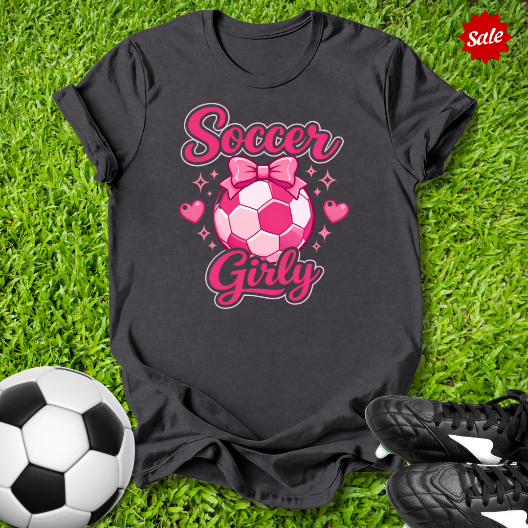 Black t-shirt with pink soccer ball design and the text Soccer Girly on grass with soccer ball and shoes