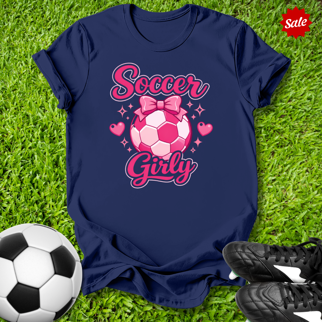 Navy blue t-shirt with pink soccer ball design  with text soccer girly  on grass with soccer ball and shoes