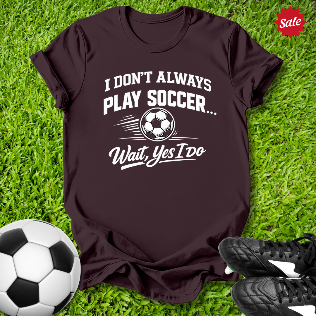Brown t-shirt with soccer-themed text on grass with soccer ball and shoes