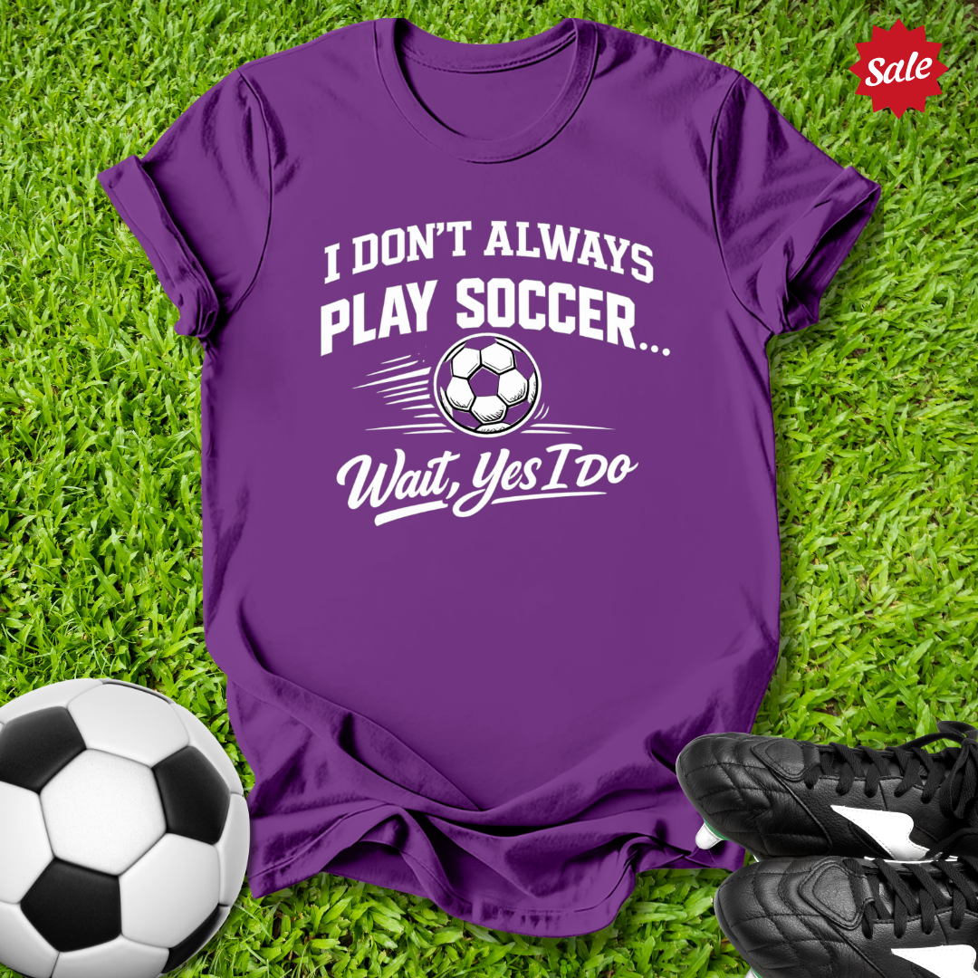 Purple t-shirt with soccer-themed text on grass with soccer ball and shoes