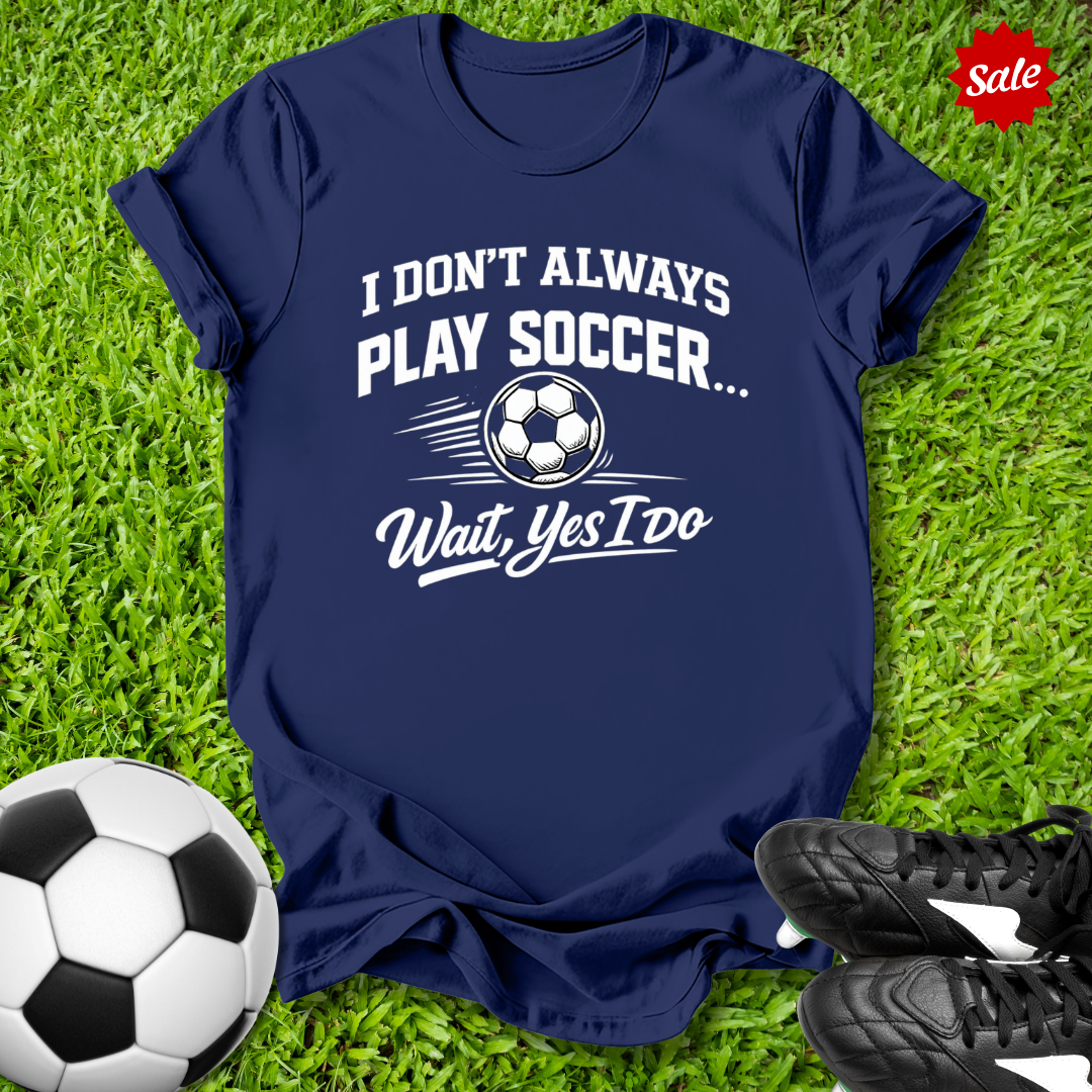 Navy blue t-shirt with soccer-themed text on grass with soccer ball and shoes