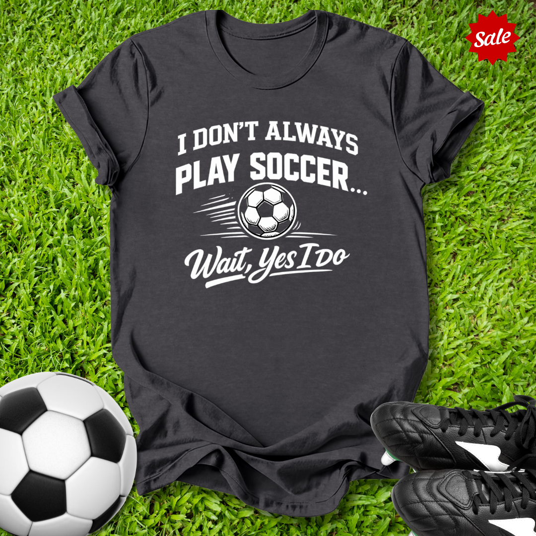 Black t-shirt with soccer-themed text on grass with soccer ball and shoes