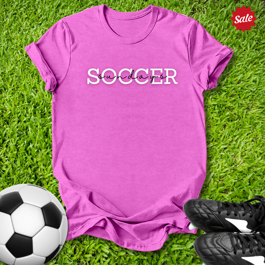 Pink t-shirt with 'Soccer Sundays' text on grass with soccer ball and shoes