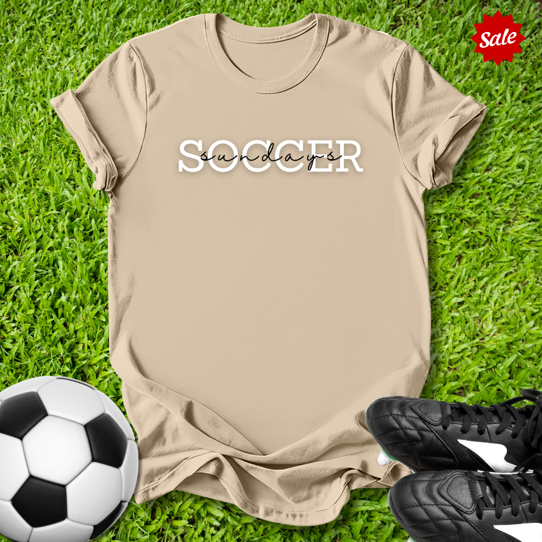 Beige t-shirt with 'Soccer  Sundays' text on grass with soccer ball and shoes