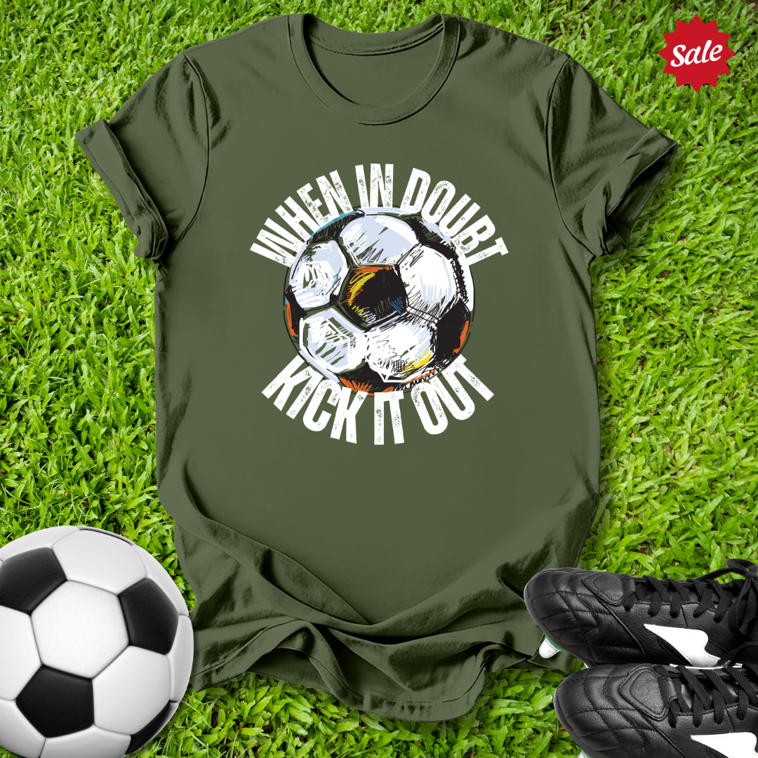 Green t-shirt with  when in doubt kick it out soccer ball graphic and text on grass with soccer ball and shoes