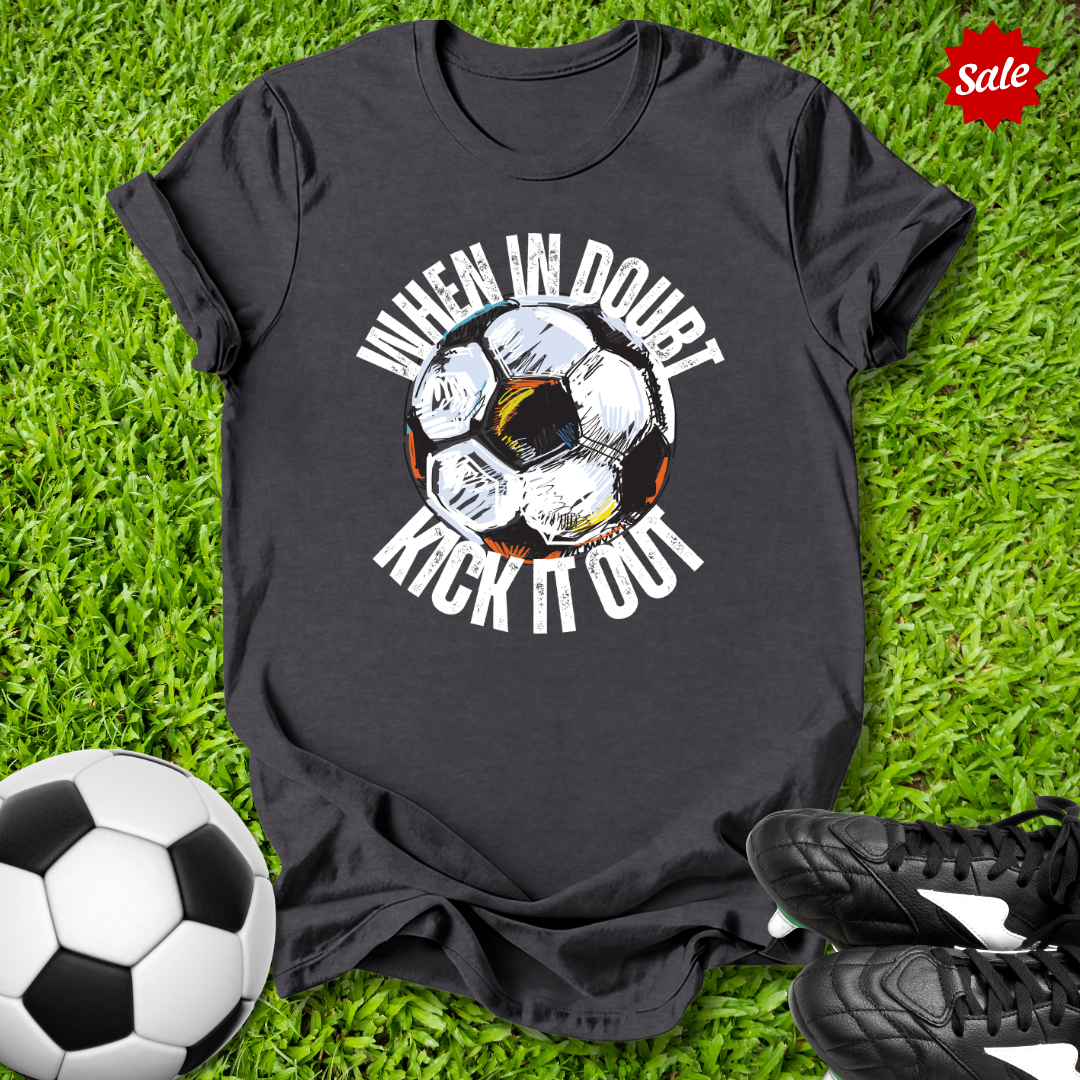 Black t-shirt with  when in doubt kick it out soccer ball graphic and text on grass with soccer ball and shoes