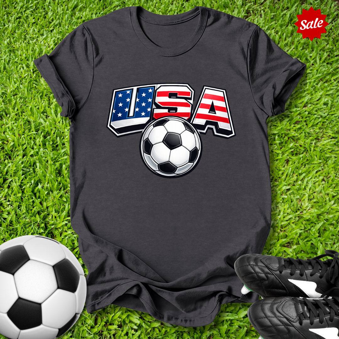 Black t-shirt with USA soccer design on grass with soccer ball and shoes