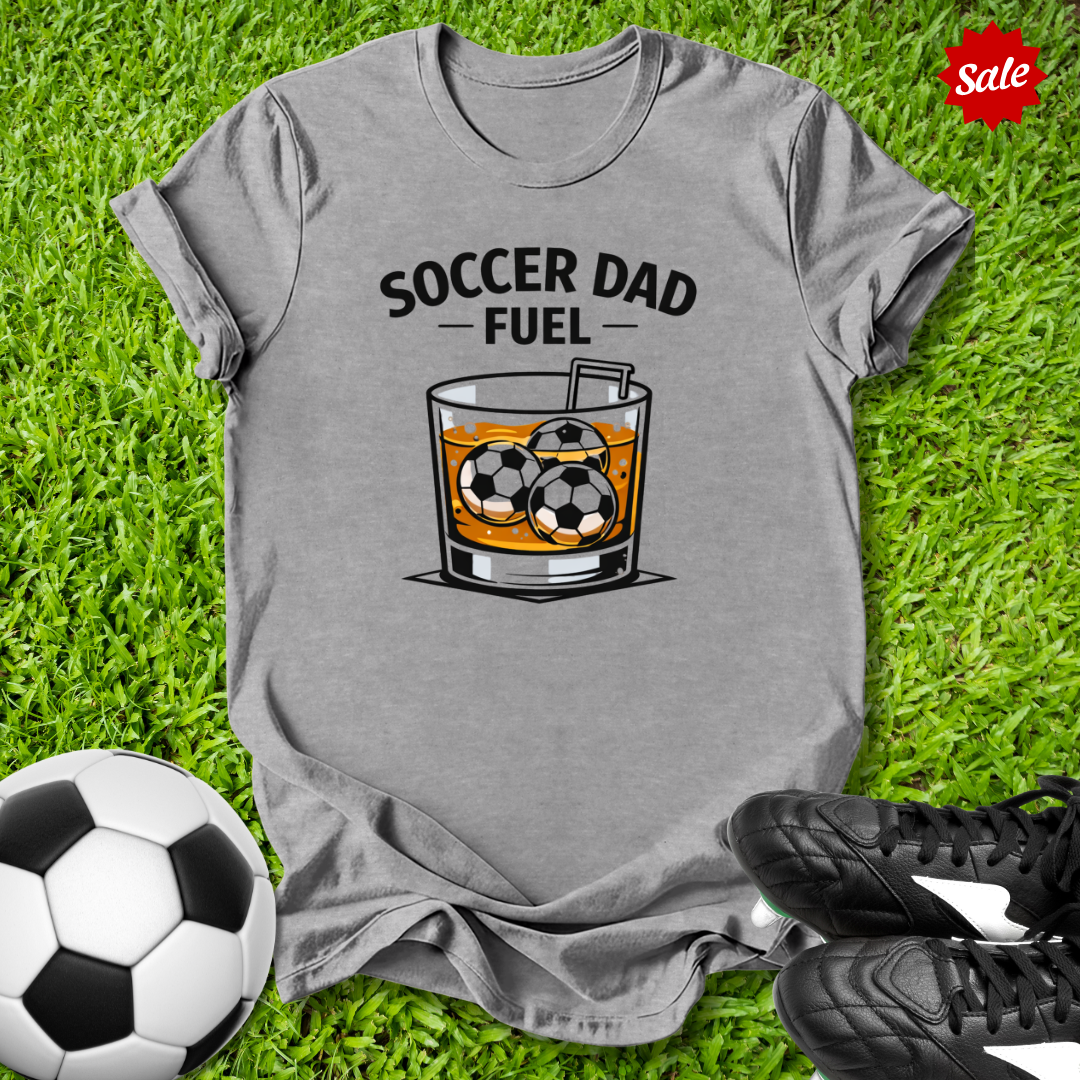 Gray t-shirt with 'Soccer Dad Fuel' graphic on grass with soccer ball and cleats