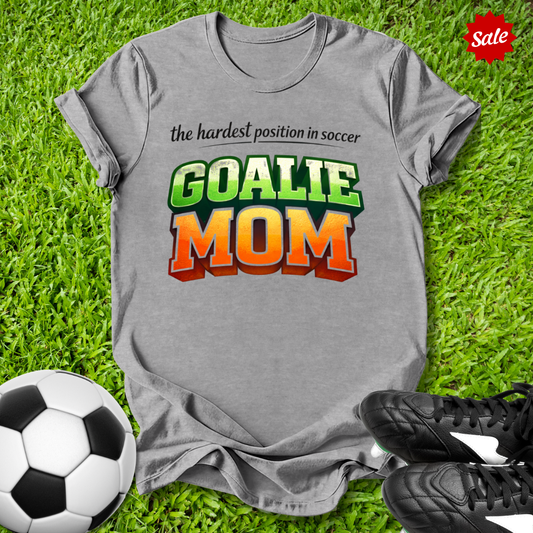 Gray t-shirt with 'GOALIE MOM' text on grass with soccer ball and shoes