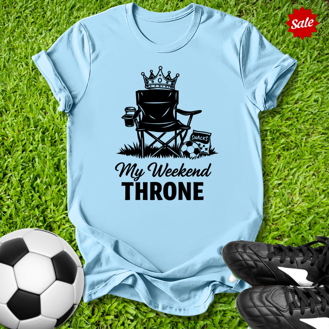 Light blue t-shirt with 'My Weekend Throne' graphic on grass with soccer ball and shoes.