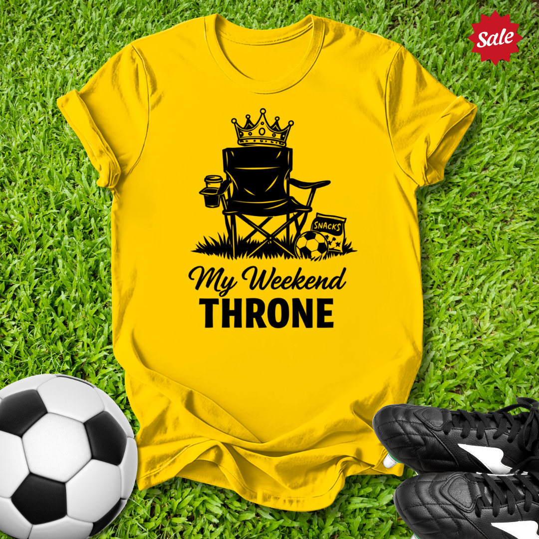 Yellow t-shirt with 'My Weekend Throne' design on grass with soccer ball and shoes.
