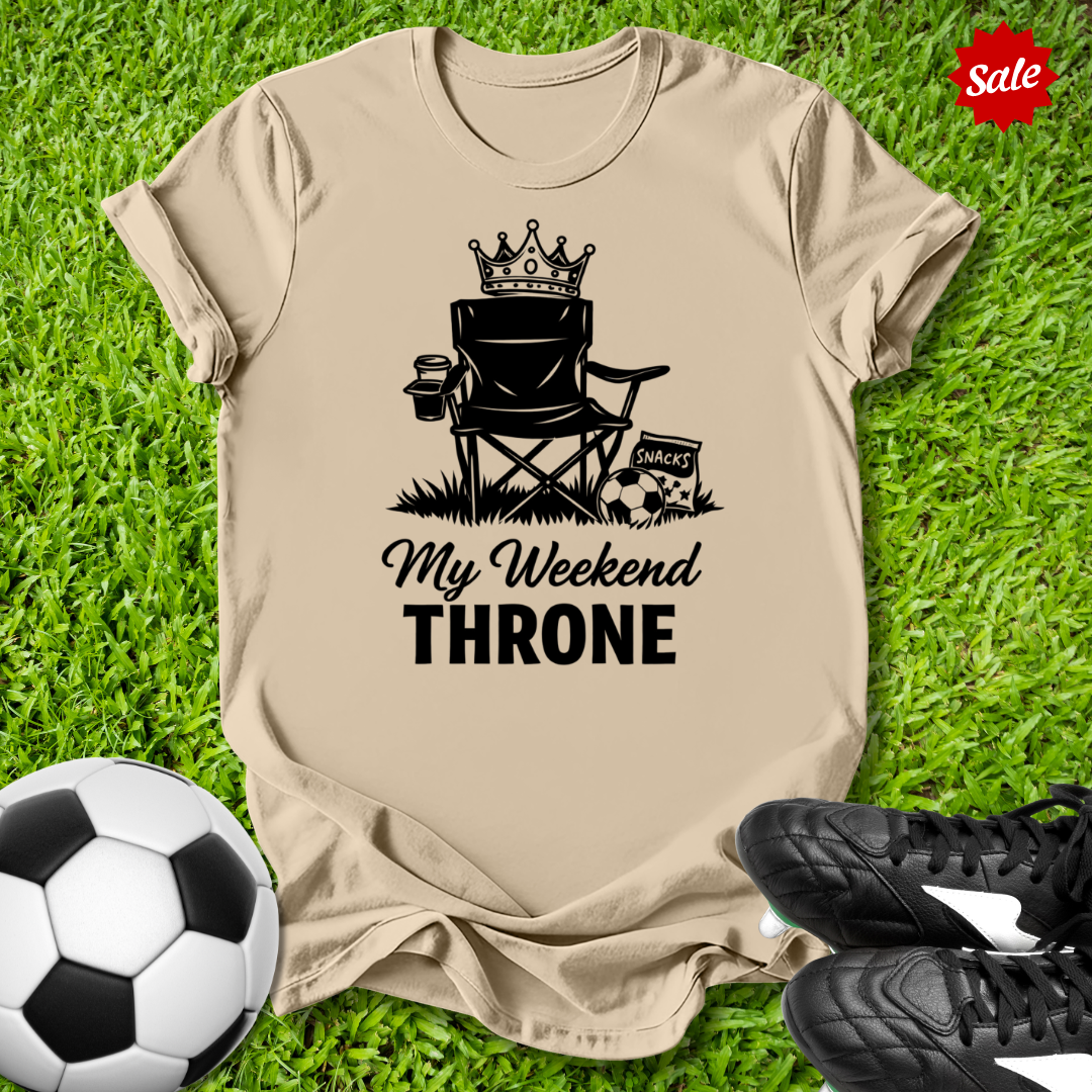 Beige t-shirt with 'My Weekend Throne' graphic on grass with soccer ball and shoes.