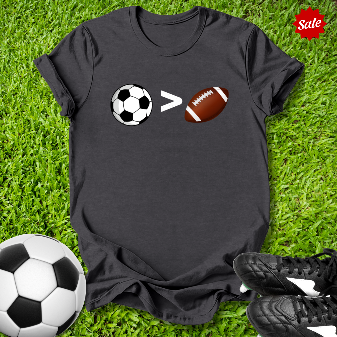 Black t-shirt with sports-themed design on grass with soccer ball and shoes