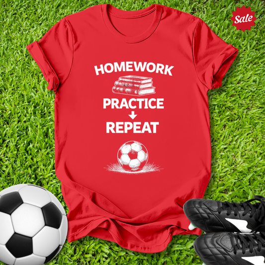 Red t-shirt with 'Homework Practice Repeat' text and soccer ball on grass with soccer ball and shoes.