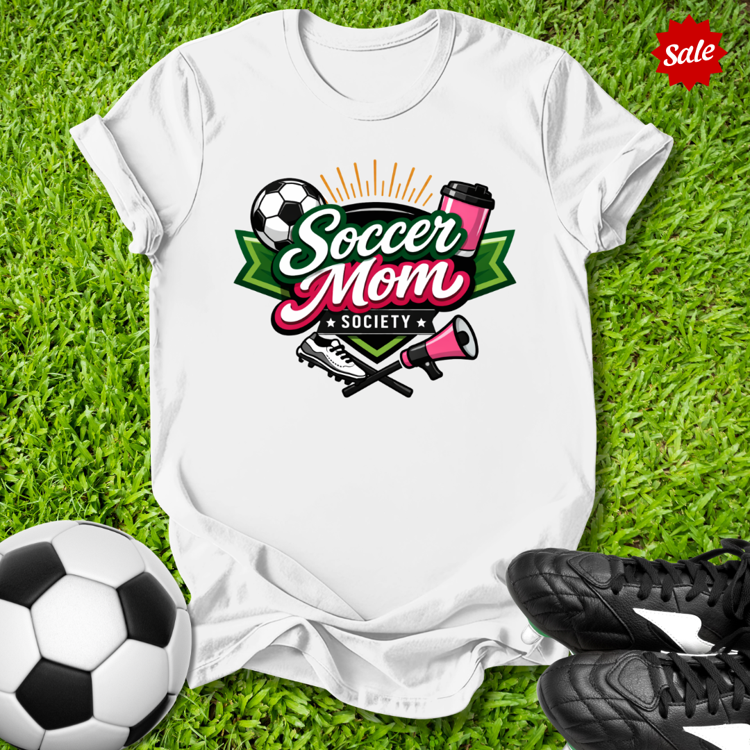 White t-shirt with 'Soccer Mom Society' design on grass with soccer ball and shoes.