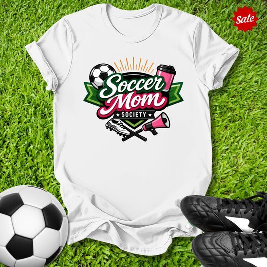 White t-shirt with 'Soccer Mom Society' design on grass with soccer ball and shoes.