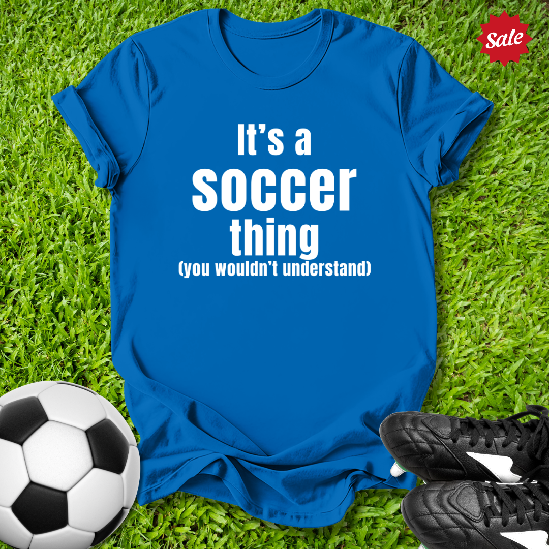 Blue t-shirt with 'It's a Soccer Thing ,You Wouldn't Understand' text on grass with soccer ball and shoes