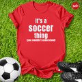 Red t-shirt with 'It's a Soccer Thing ,You Wouldn't Understand' text on grass with soccer ball and shoes