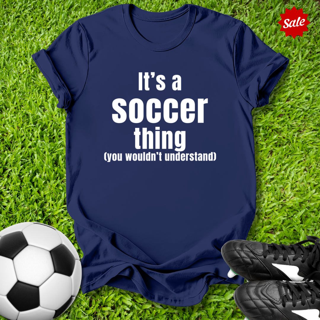 Navy t-shirt with 'It's a Soccer Thing ,You Wouldn't Understand' text on grass with soccer ball and shoes