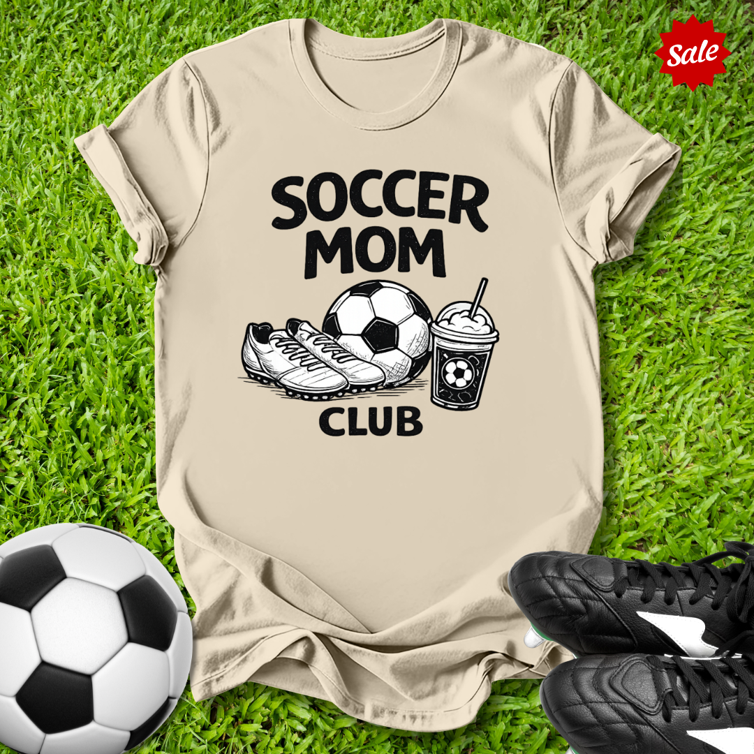 Beige Pink t-shirt with 'Soccer Mom Club' text on grass with soccer ball and shoes