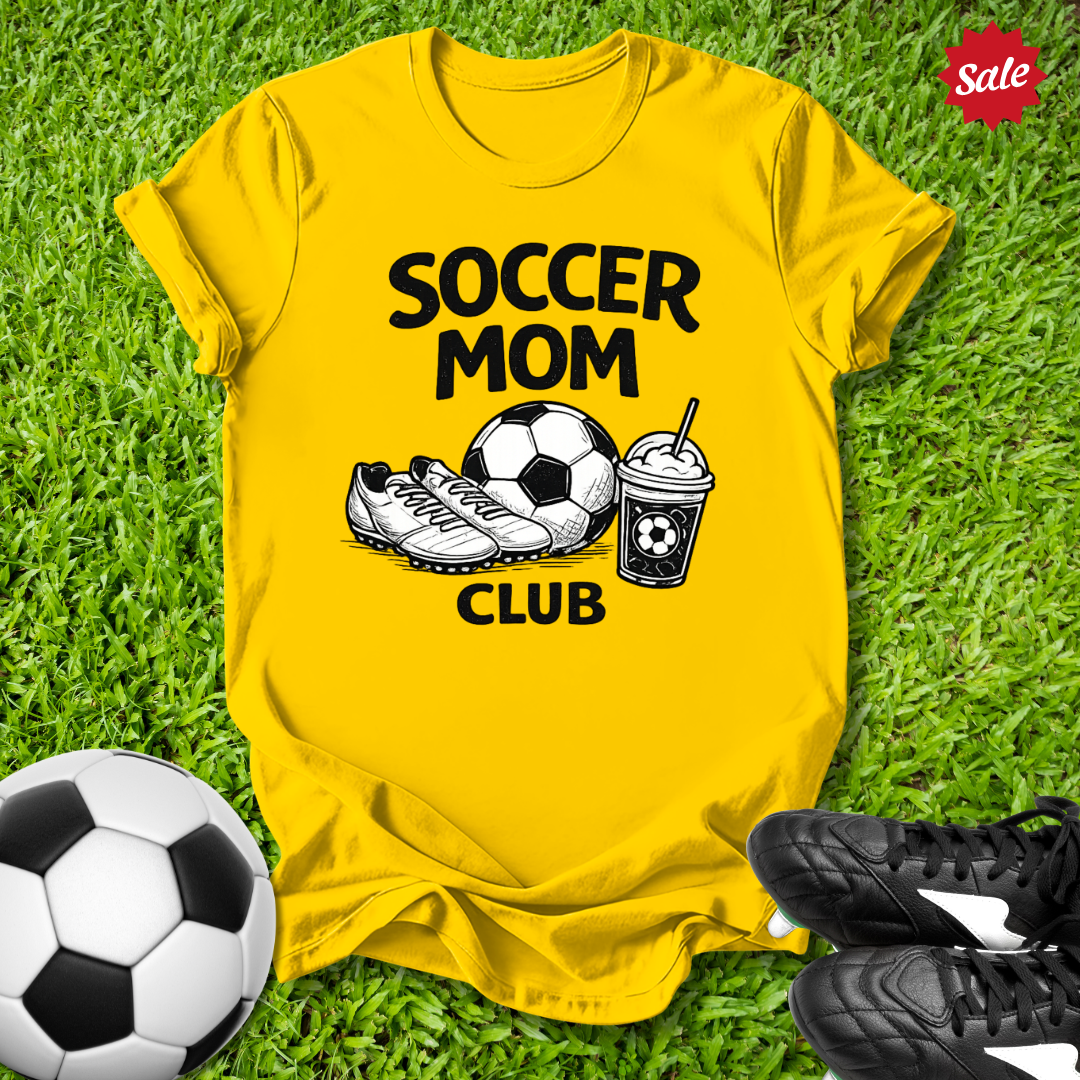 Yellow Pink t-shirt with 'Soccer Mom Club' text on grass with soccer ball and shoes