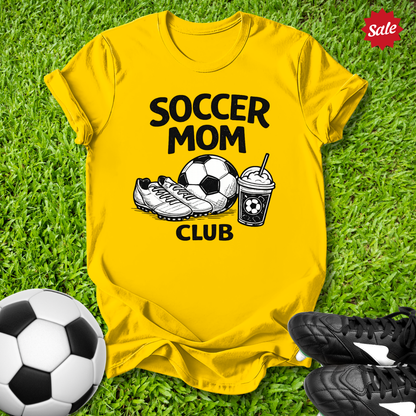 Yellow Pink t-shirt with 'Soccer Mom Club' text on grass with soccer ball and shoes