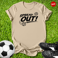 beige  t-shirt with 'Spread Out!' text on grass with soccer ball and shoes