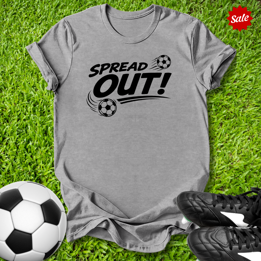 Gray t-shirt with 'Spread Out!' text on grass with soccer ball and shoes