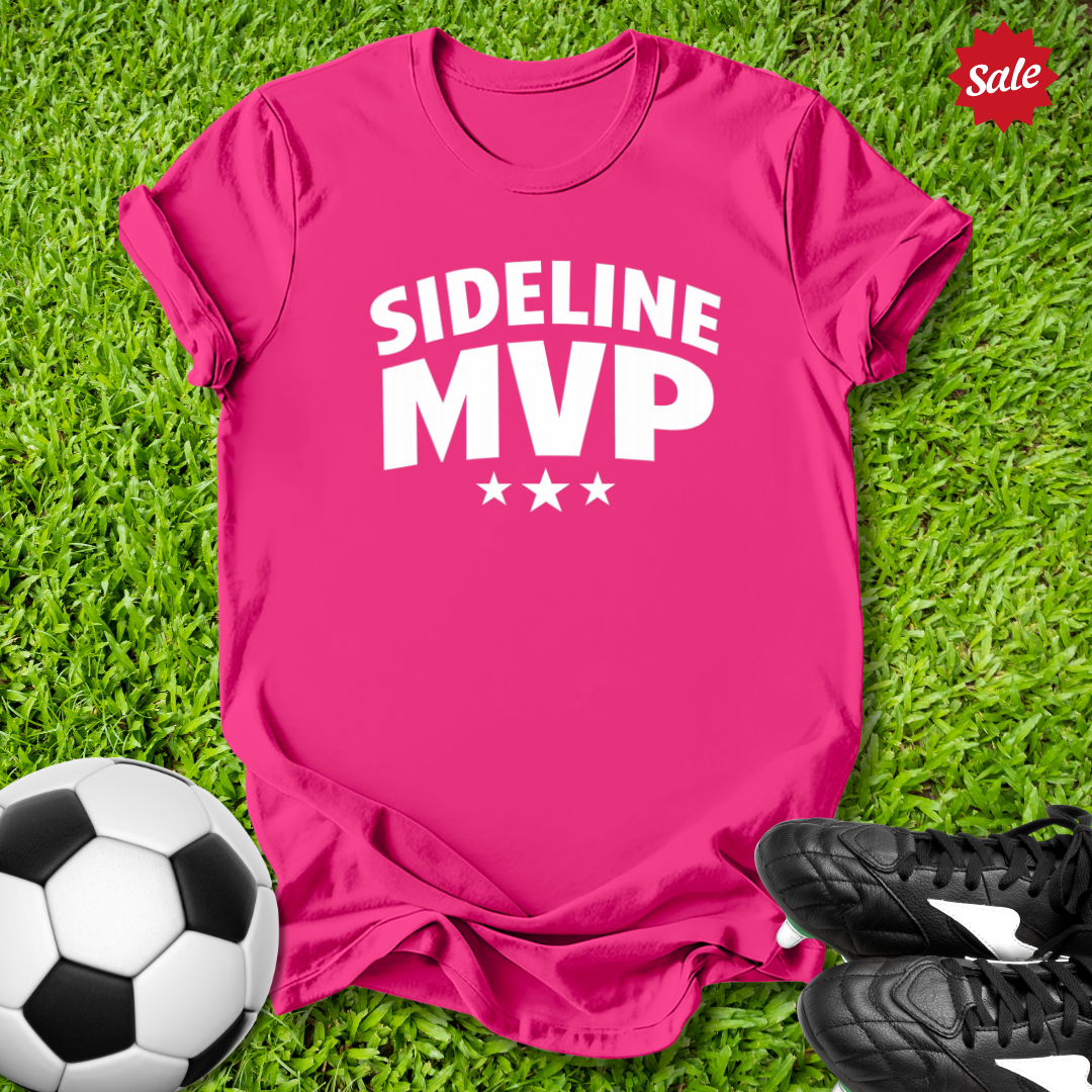 Pink t-shirt with 'Sideline MVP' text on grass with soccer ball and shoes