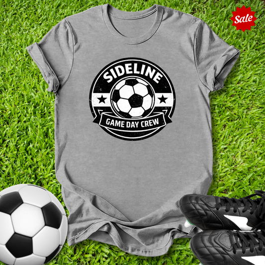 Gray t-shirt with 'Sideline Game Day Crew' design on grass with soccer ball and shoes.
