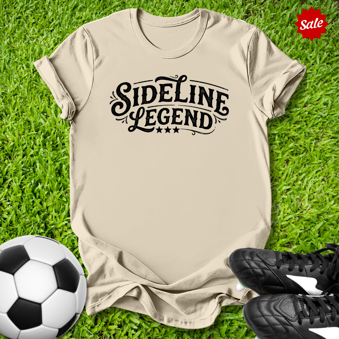Beige t-shirt with 'Sideline Legend' text on grass with soccer ball and shoes