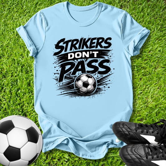 Light blue t-shirt with 'Strikers Don't Pass' graphic on grass with soccer ball and shoes.