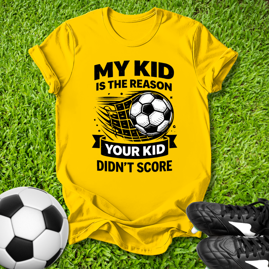 Yellow t-shirt with soccer-themed text on grass with soccer ball and shoes