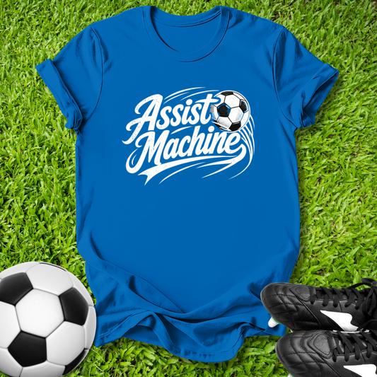 Blue t-shirt with 'Assist Machine' graphic on grass with soccer ball and shoes