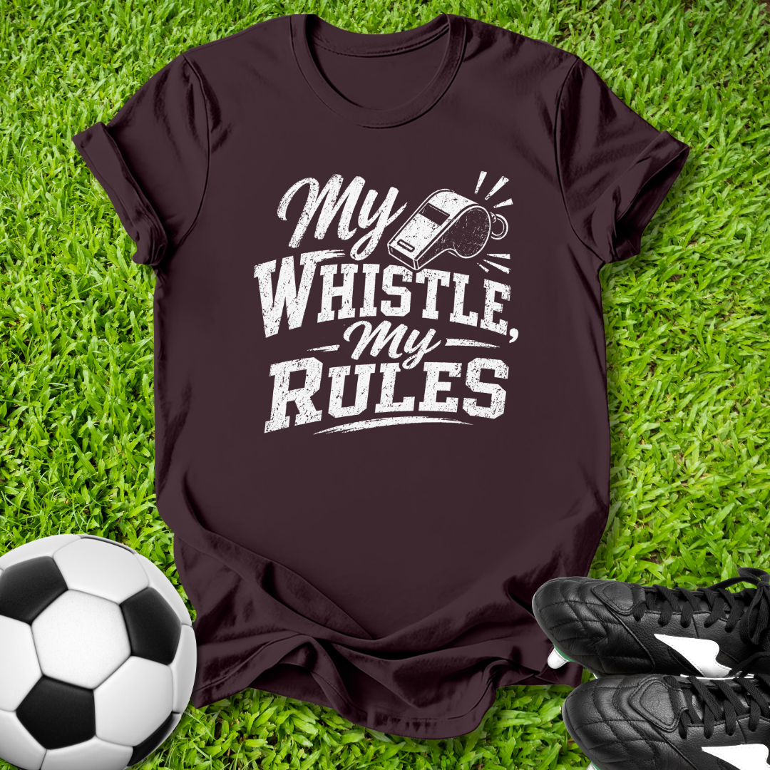 Maroon t-shirt with 'My Whistle, My Rules' text on grass with soccer ball and shoes.