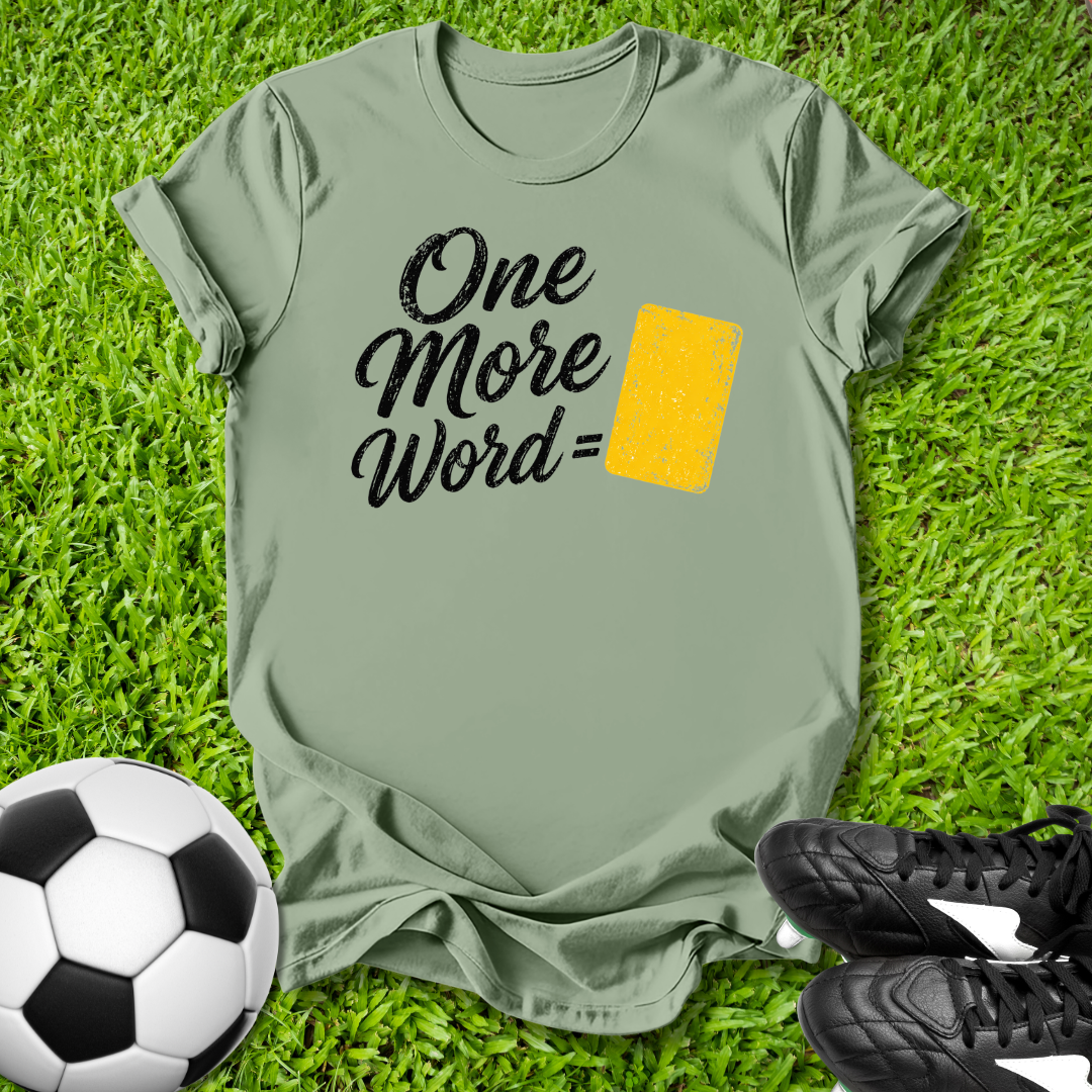 Green t-shirt with 'One More Word' text on grass with soccer ball and shoes